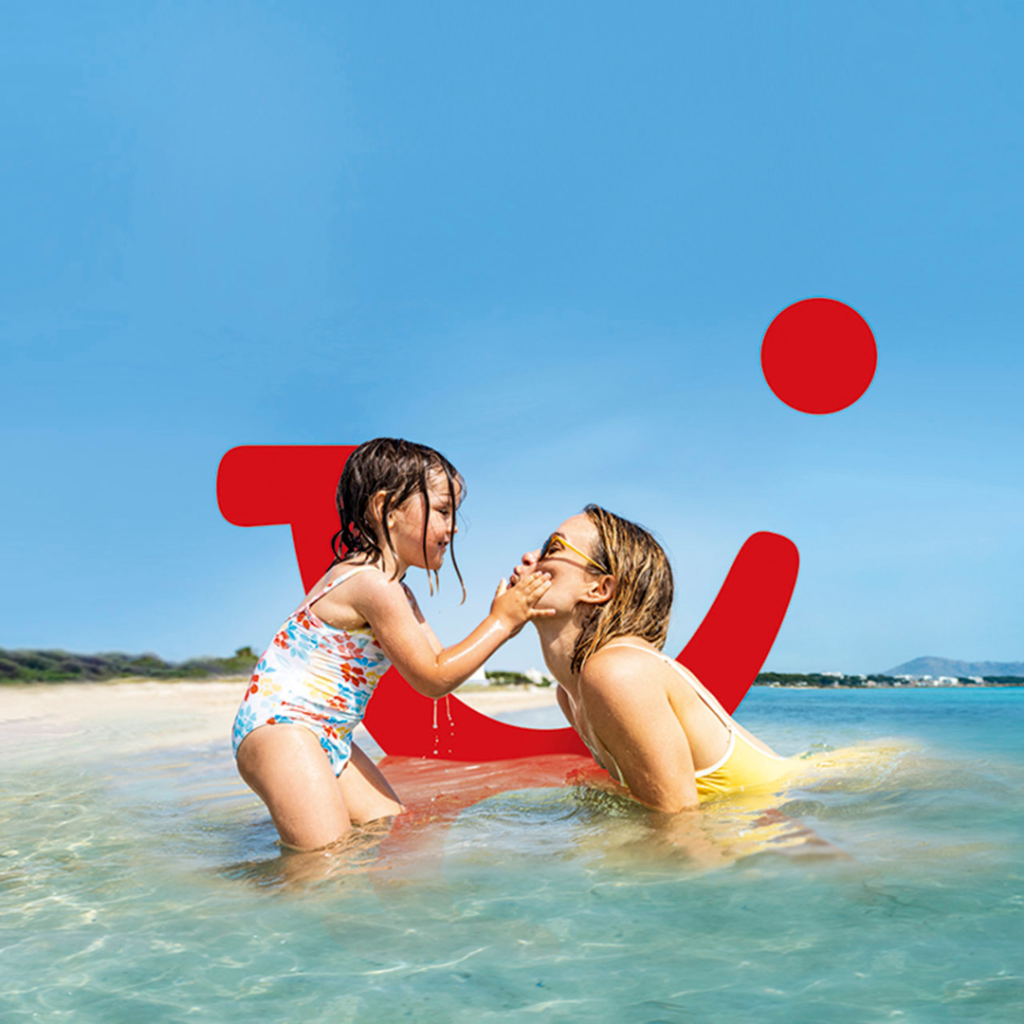 A mother and child playing in the sea with the TUI logo behind them.