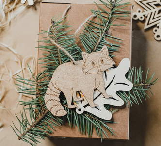 Eco friendly christmas - top down view of wooden raccoon bauble with pine needles and wooden snowflake baubles on a brown paper background
